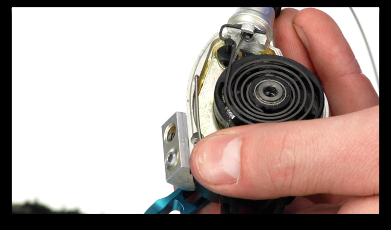 Step 4. With the cover off you should be able to spot the end of the cable just underneath the large spring. Take note of where it sits and the path that it takes to exit the shifter. You should be able to dislodge the head of the cable by gently pushing the cable into the shifter through the barrel adjuster. Completely remove it from the shifter.