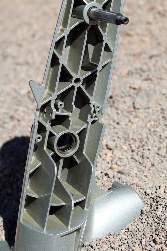 You're looking at the sturdy upright that holds your bike in place. The internal webbing keeps things stiff and flex free. At the top of the photo you can see the axle that the surrogate wheel uses, and at the bottom you'll find the roller bearing (and sealed ball bearing hidden from view) that the drive axle spins upon. The bottom of the burly frame also features independently adjustable feet to let you dial in a stable position on uneven surfaces.