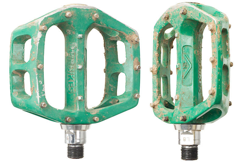 With so many high end boutique pedal options to pick from, all who seem to be bragging about being thinner and lighter than the competition, it's easy to forget about some of the more sensible options out there. Enter DMR's V12 pedals. With their classic shape and proven internals, the V12's wave their middle finger proudly to all of the latest and more pretentious alternatives. Yes, there are far thinner pedals, there are lighter pedals, and there are both less expensive and far more expensive options, so what does DMR bring to the table with their V12's? The fact that the V12 is still a very strong seller and that it's common to see them on bikes no matter where you are speaks volumes for the amount of riders that are simply looking for a reasonably priced pedal with good bite and that will last a long time without having to worry about destroying them with a single rock strike. The burly body uses a shape that many old school riders will recognize as working well, although it should be noted that there is no built-in concave to it, the placement of the pins will have a similar effect. Ten M4x0.7x8 set screws are used per side, as opposed to closed top pins that may be a bit more resilient to damage, but won't provide as much traction. The 115 mm x 95 mm platform is larger than some, as is the 25 mm body height. Inside you'll find a simple and easy to work on system that uses a single sealed bearing at the outer edge combined with a bushing for the inner section of the chromed CroMoly axle to spin on. All replacement parts are available through local dealers or off the DMR site and the pedals are very easy to work on.  Seven color options: Diamond Black, Pure White, Polished, Sky Blue, Green, OX blood and Chrome.