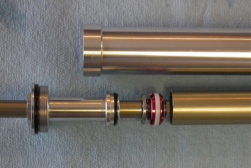 This is the anodized rebound piston inside the Vengeance. The spring loaded shim at the left side (top) of the piston acts as the check valve, with the shims on the opposite side controlling the high speed rebound stroke. The large threaded top cap on the far left seals the damping oil within the silver outer tube.