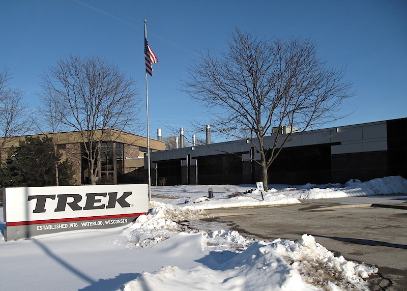 <span style='font-size:18px'>The unassuming building that houses Trek's world headquarters</span><br><br>Trek's world headquarters are located in Waterloo, Wisconsin, a sleepy town filled with farms and quaint houses, and is only a few miles from where the first Trek bikes were welded together in a red barn. This location is not only Trek's spiritual residence, but also home to their in-house carbon frame manufacturing. Part office building and part technological safe house, its appearance from the outside deceives its forward thinking office space layout and warm interior. You won't find pint-sized cubicles squeezed in to maximize floor space, instead, a more open floor plan is employed. Those who design wheels sit next to those who work with tires, including Keith Bontrager himself.