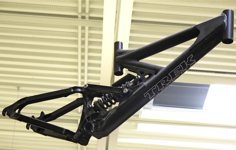 <span style='font-size:18px'>Old school prototype hanging from the ceiling in the ACG room</span><br><br>A perfect example of something that was tested, but never made available to the public. This all black special uses a triangulated rear end and two links to control wheel path and shock rate, but its colossal head tube reinforcement is what caught my eye. Burly!