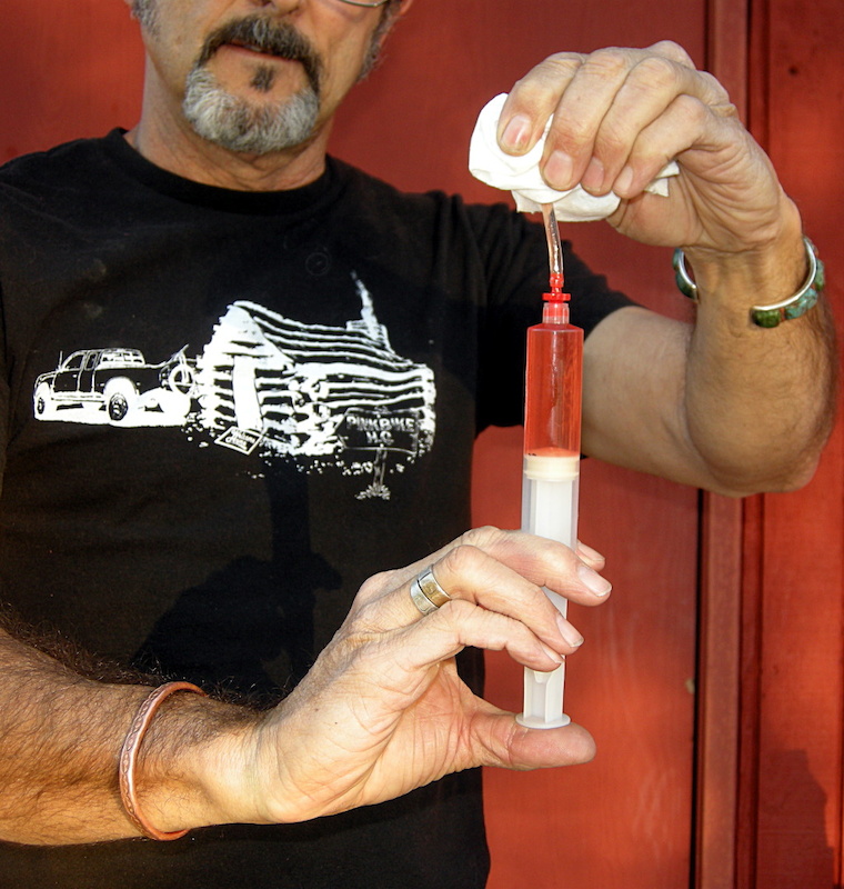 Evacuate air from syringe by pushing the bubbles and fluid into an absorbent cloth. Wear eye protection to prevent fluid spew from ruining your day.