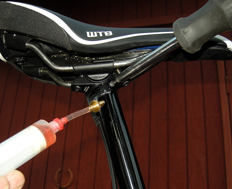 Give the remote syringe a strong push and then unscrew the seatpost syringe and screw in the proper plug. It has an O-ring so the plug only needs to be tightened to a snug fit. A little fluid will escape.