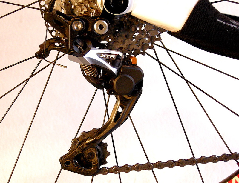 Shimano s XTR Shadow Plus rear derailleur is similar to the standard item with the addition of a friction clutch and housing at the cage pivot. The clutch engages only when the cage swings forward.