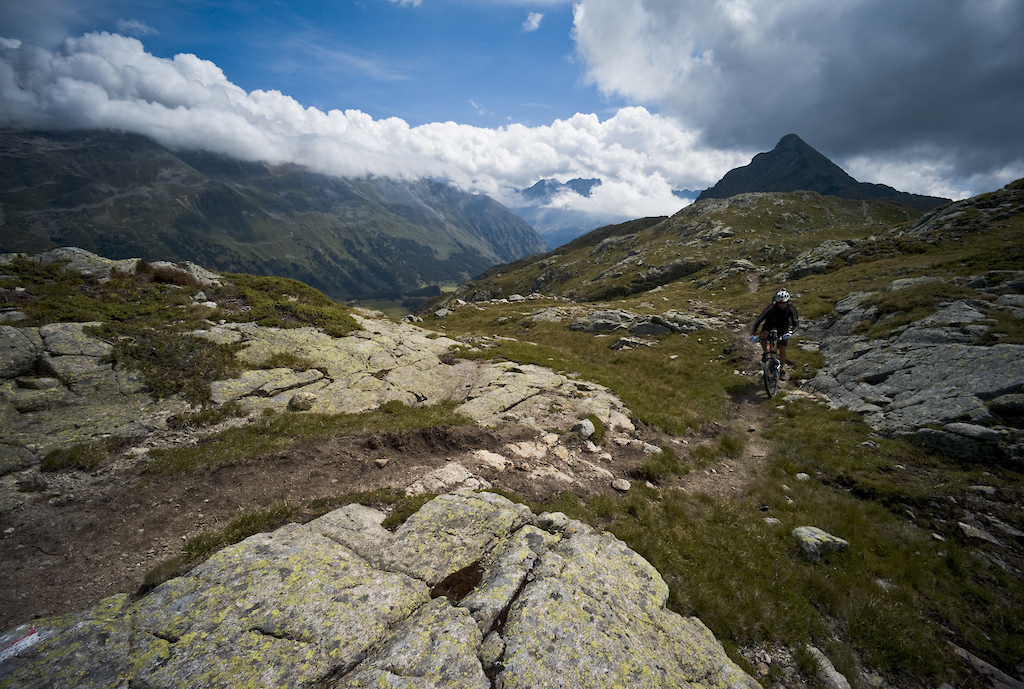 <span style='font-size:12px'>Taking the Bernina Express train out of St Moritz delivered us to the Bernina Pass at 2252m (pictured). The line is 100 years old and still runs with Swiss punctuality, unlike ourselves who arrived at our Monastery accommodation that night 2 hours late after having taken 2 wrong turns en route.</span><br><br>I trace the line of our trail with my gaze, as it drops down to the azure blue Lake Giacomo far below. To any casual passerby, the trail we're about to drop into looks far from welcoming; it's a twisting, foot wide swathe of loose gravel and fist sized rocks that cuts back and forth across an exposed mountainside that itself feels a long way from anywhere, but to us it's the deserved fruit of our labour, reached by an hour's climb and a final bike shouldering scramble across some very exposed scree chutes. Right now loose gravel and fist sized rocks have never looked so inviting. I drop my seat and roll into the entrance of the trail sporting a cheek to cheek grin.