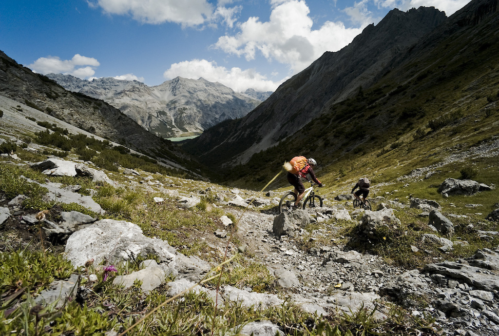 <span style='font-size:12px'>Another col, another descent. And so the pattern for each day is set. The AR is all about earning your rewards it seems.  Despite the abundant lifts en route, t's no free ride.</span><br><br>We start our epic in St Moritz by taking a historic train up to the 7000 ft Bernina Pass. The red Bernina Express sports a dedicated carriage in which to hang our steeds, but we've made the wrong assumption that the 